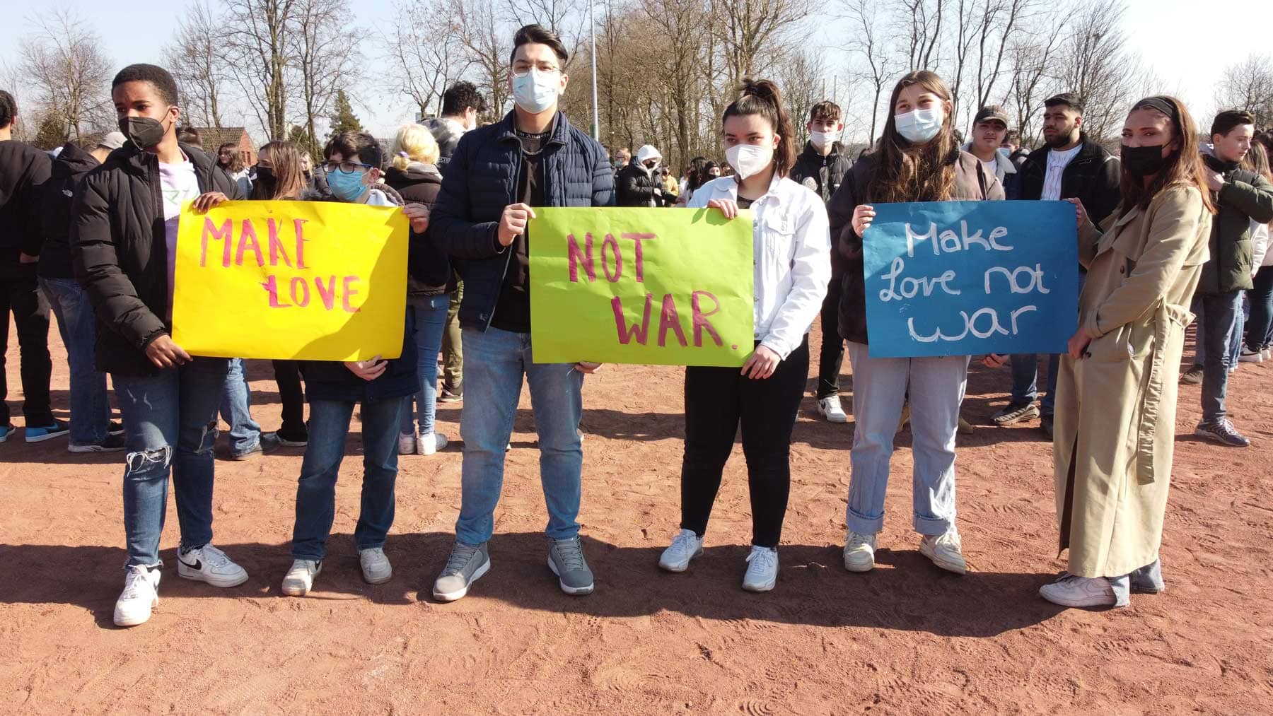 Schülerinnen und Schüler halten Plakate "Make Love Not War" hoch.