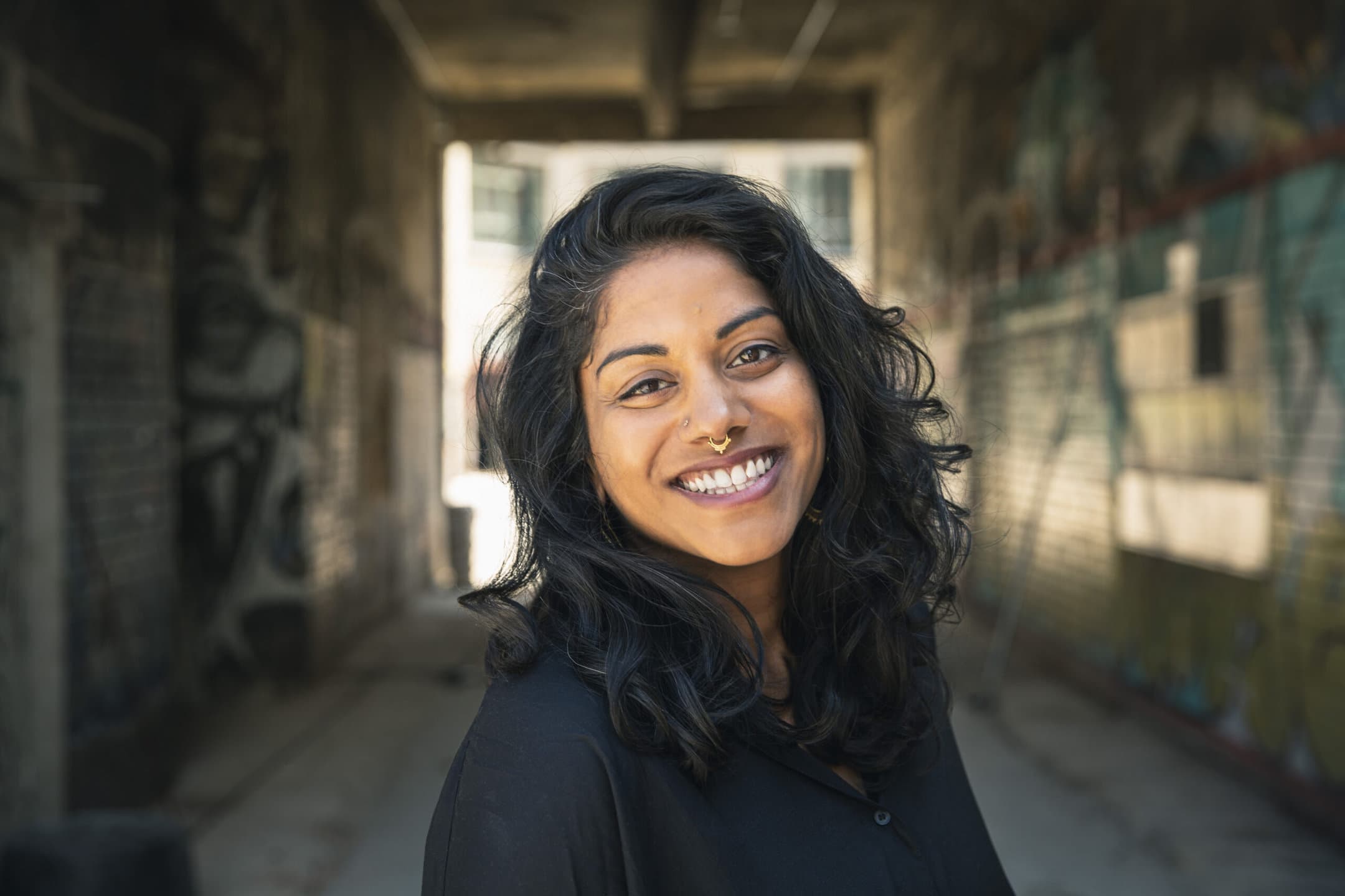 Portraitfoto von Alli Kamalanathan, im Hintergrund ist ein Tunnel zu erkennen