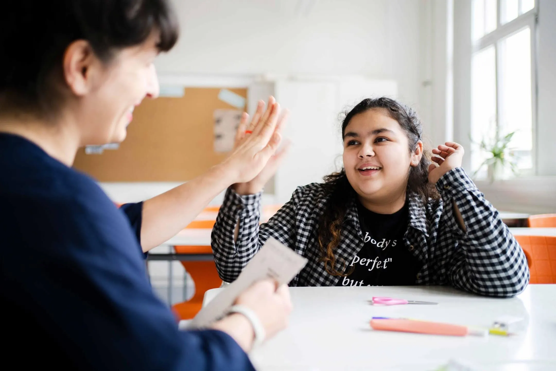 Sachsen Fellow 2018 Susanne Keichel sitzt mit einer lächelnden Schülerin an einem Tisch und gibt ihr ein High Five