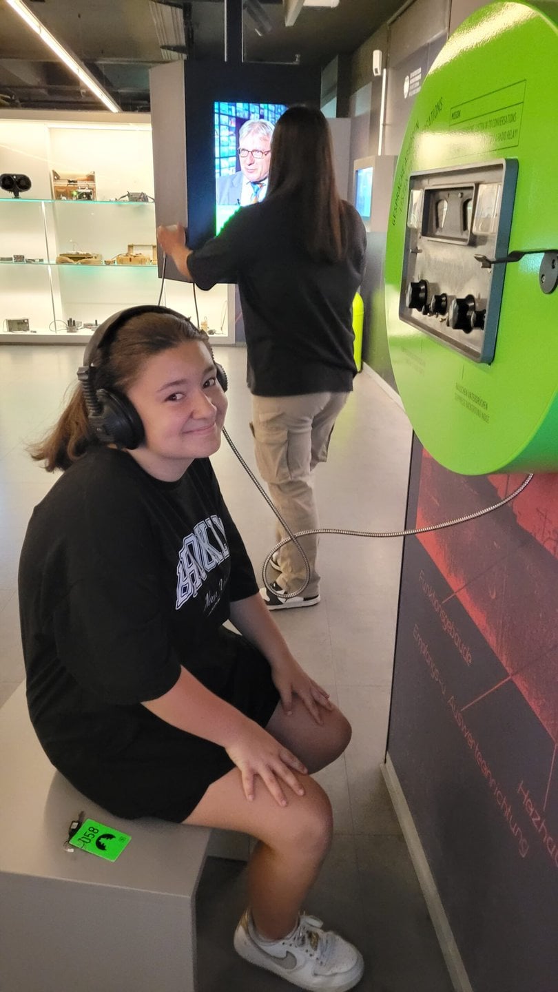 Schülerin mit Kopfhörern an einer Station im Spionagemuseum Berlin