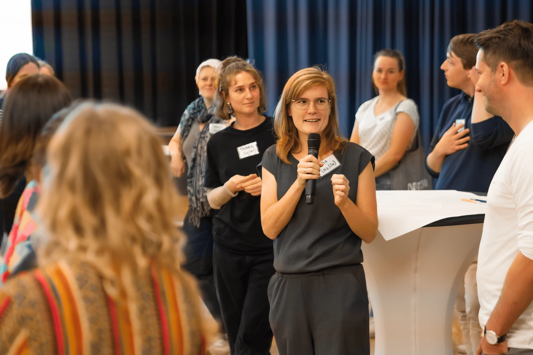 Eine Frau hält ein Mikrofon vor einer Gruppe von Menschen.